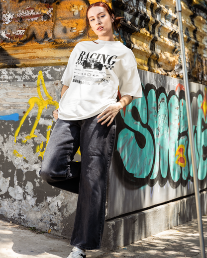 Person wearing a white t-shirt with racing text and graphics, leaning against a graffiti-covered wall.